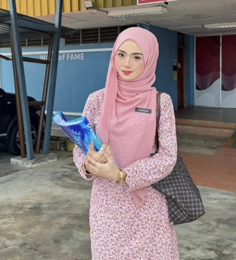 Seorang cikgu tadika memegang buku di sekolah